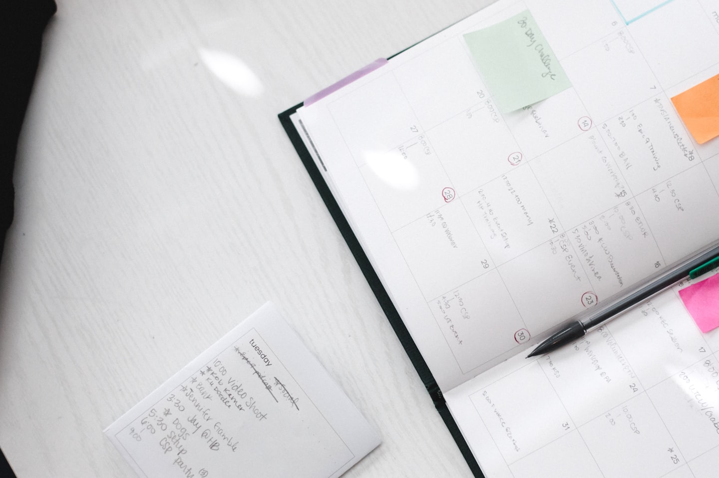 Open planner with handwritten notes and sticky notes on a wooden desk.
